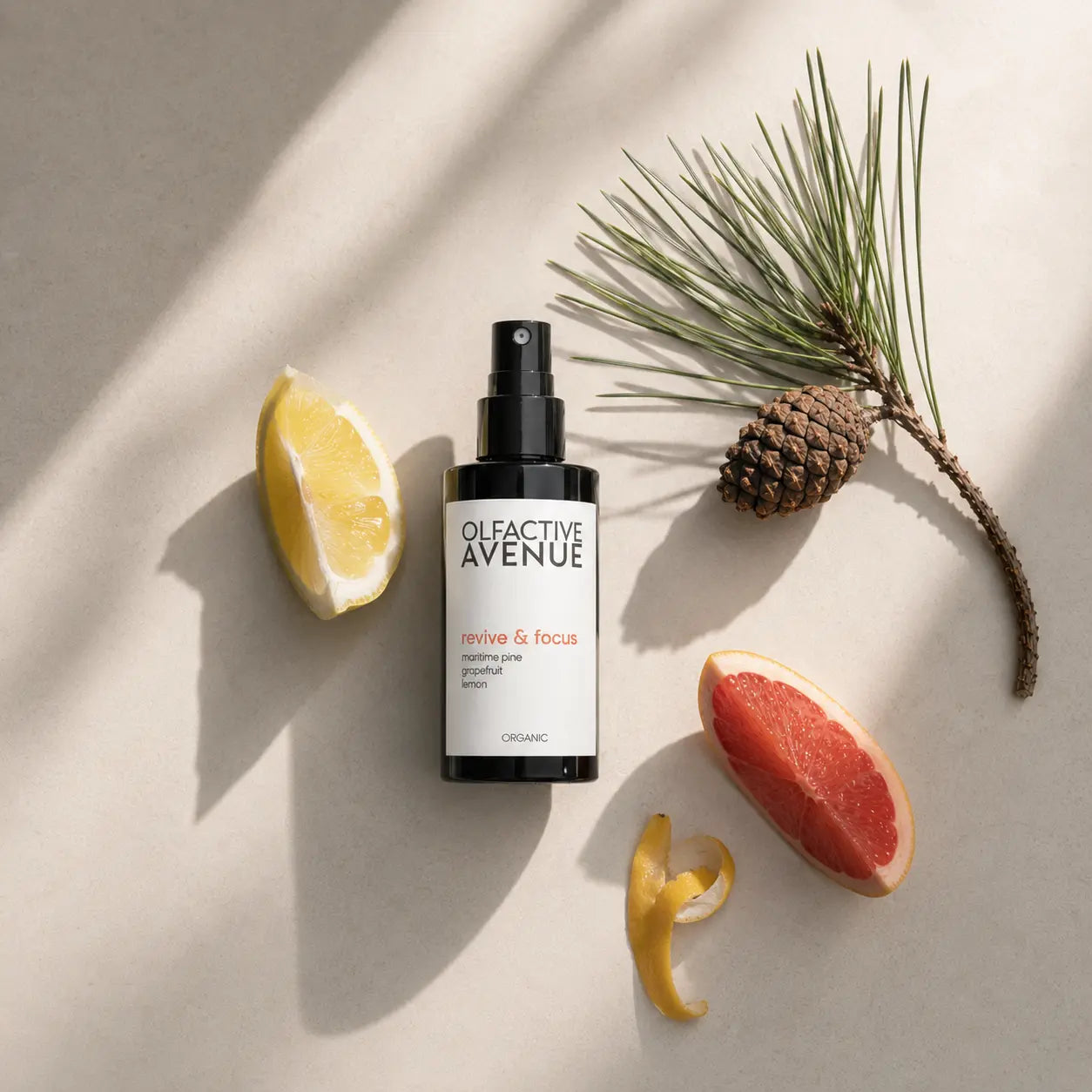 Revive & Focus Raumspray von The Olfactive Avenue als Flatlay mit Zitrone, Grapefruit und Kiefer auf hellem Naturstein.
