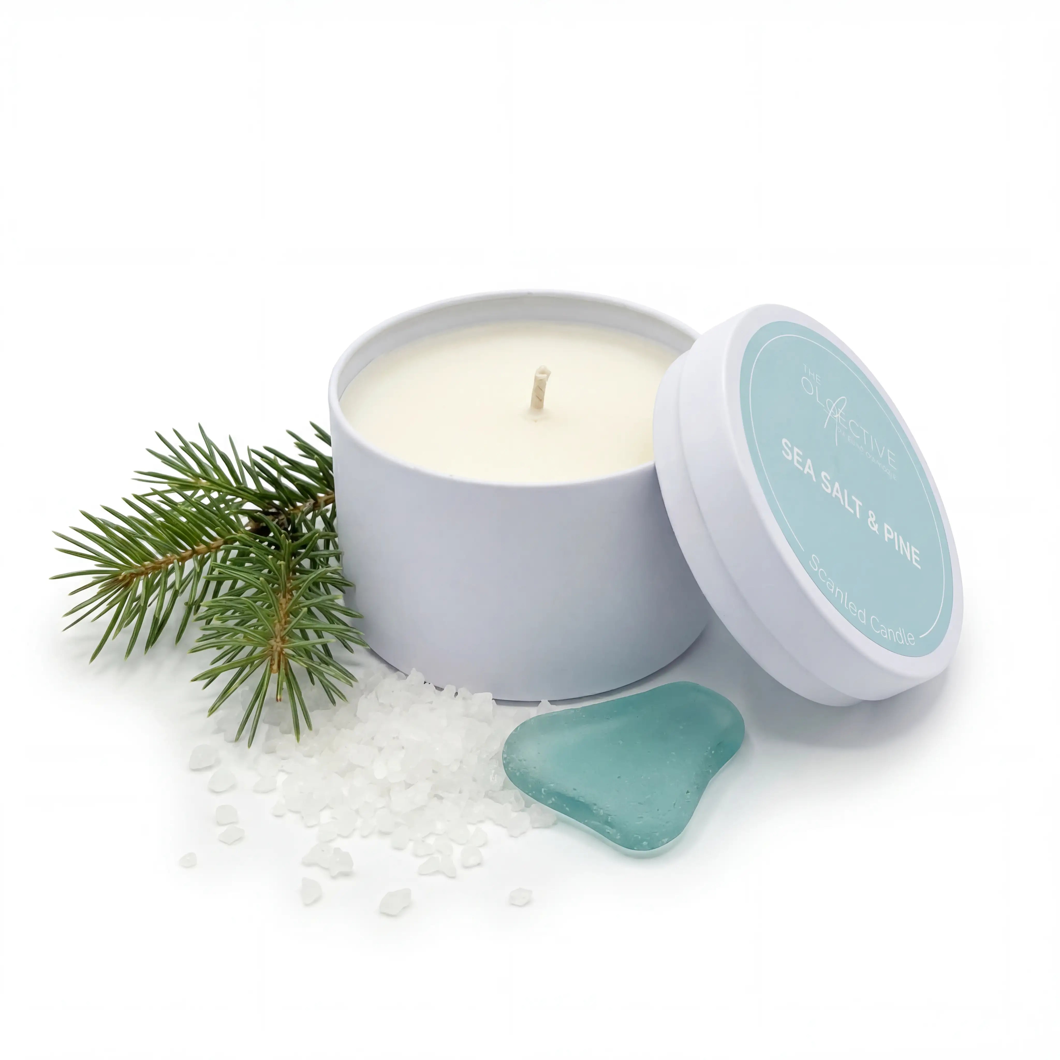 Professionelle Produktaufnahme der geöffneten Sea Salt & Pine Kerze. Das Set auf weißem Grund zeigt die Kerze, den Deckel, Kiefernzweige und blaues Seeglas – ideal zur Visualisierung der maritimen Duftnoten.