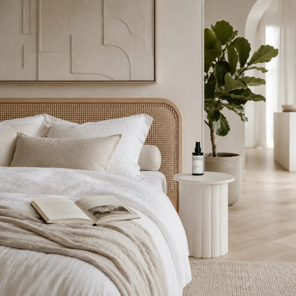 Calm & Sleep Bio-Raumspray von The Olfactive Avenue auf weißem Nachttisch im hellen Schlafzimmer mit Rattanbett und grüner Zimmerpflanze.