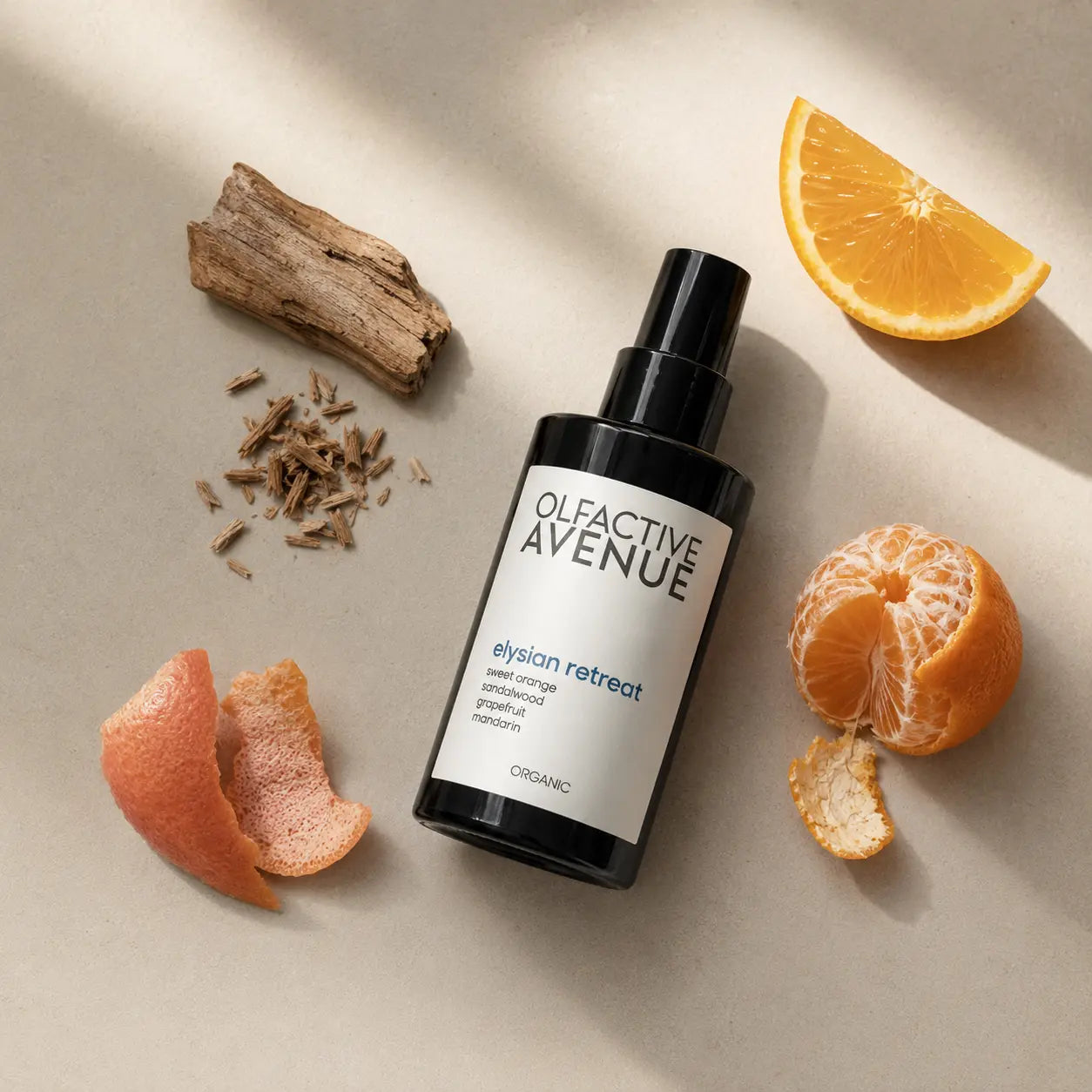 Elysian Retreat Bio-Raumspray von The Olfactive Avenue als Flatlay mit Orange, Mandarine, Grapefruit und Sandelholz auf hellem Untergrund.