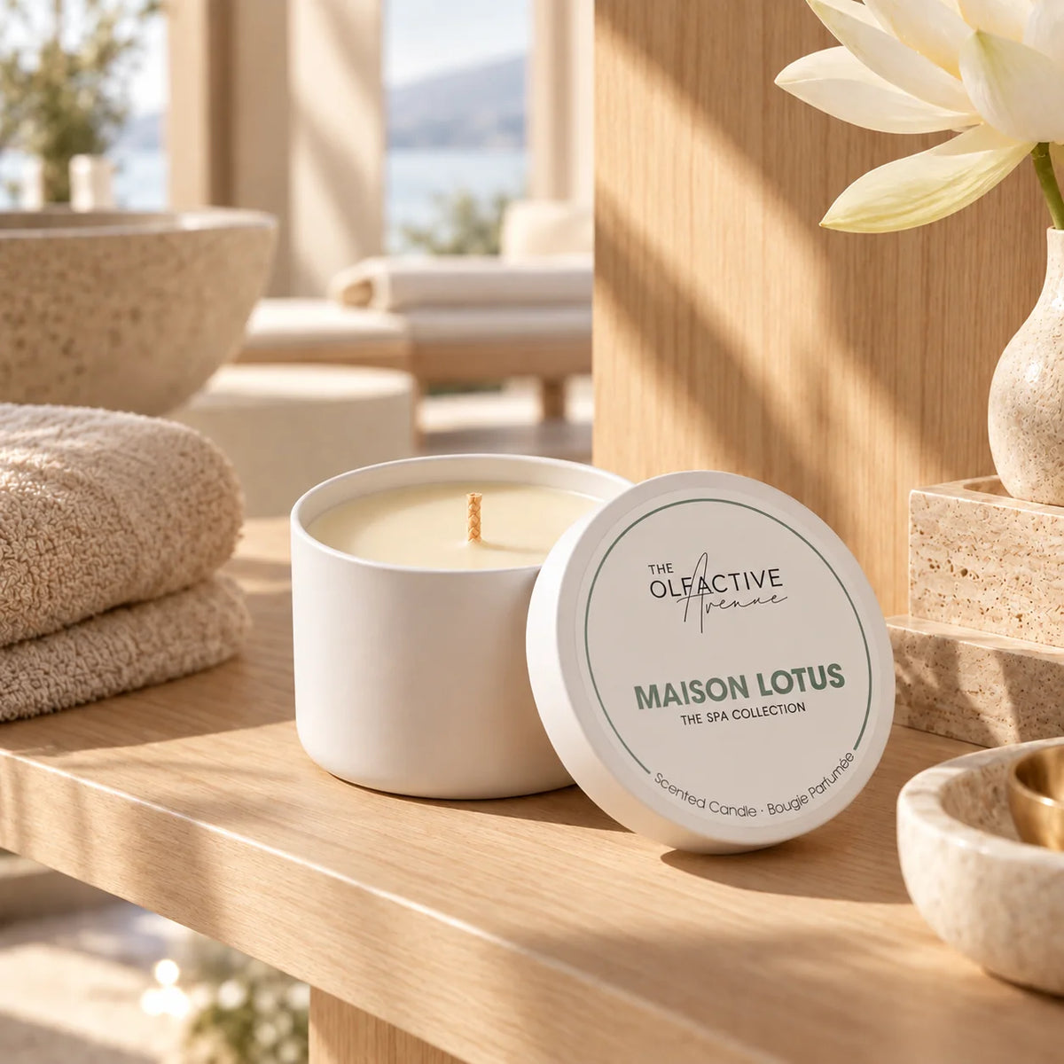 Maison Lotus Duftkerze von The Olfactive Avenue im hellen Spa-Ambiente mit Handtüchern und Steinschalen, The Spa Collection [KI]