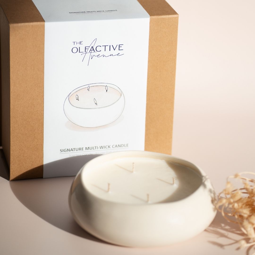 Die Mehrdochtkerze neben ihrer hochwertigen, minimalistischen Geschenkverpackung aus Naturkarton – perfekt für Design-Liebhaber.