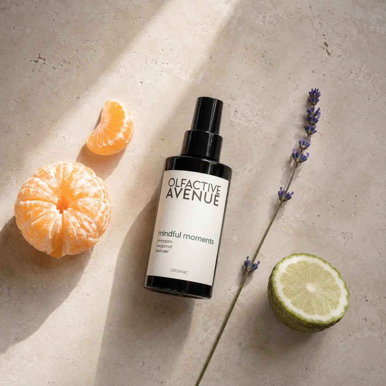Mindful Moments Bio-Raumspray von The Olfactive Avenue als Flatlay mit Mandarine, Bergamotte und Lavendel auf hellem Naturstein.