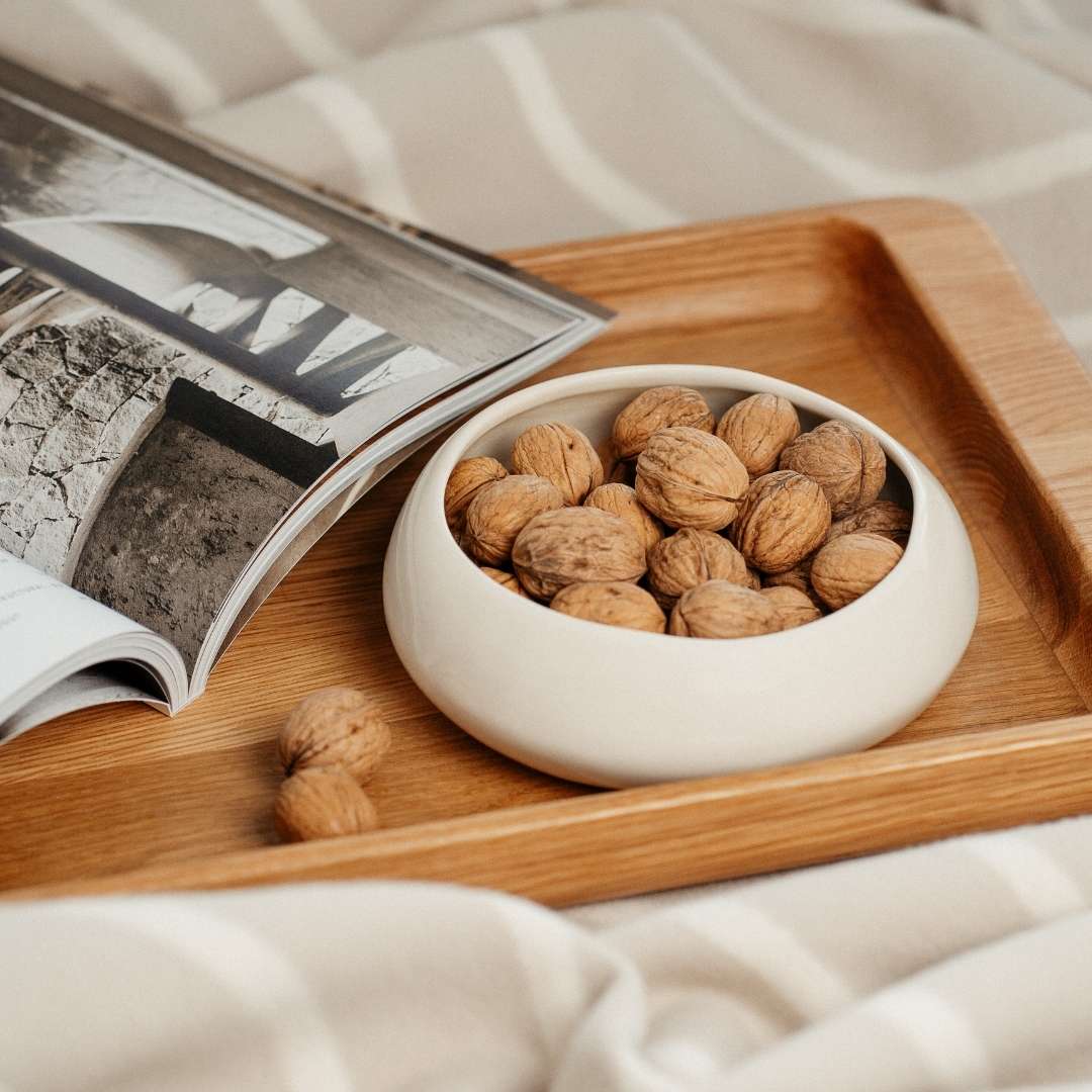 Nachhaltiges Design: Die leere Keramikschale der TOA Mehrdochtkerze wird als stilvolle Nussschale auf einem Holztablett wiederverwendet.