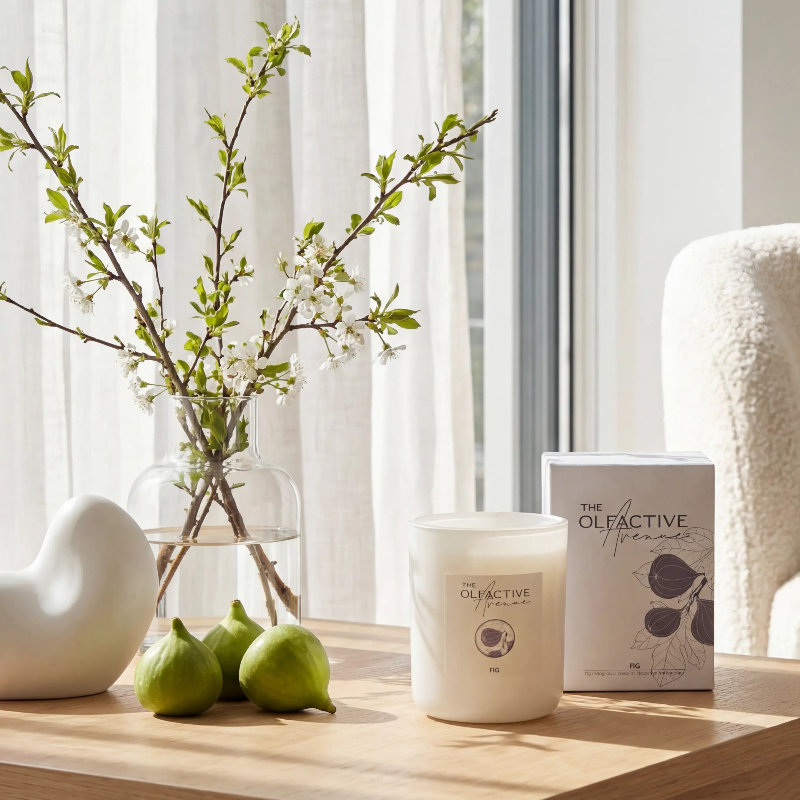 Produktfoto der Olfactive Avenue FIG Duftkerze in einem hellen, skandinavischen Wohnzimmer. Die handgegossene Kerze steht auf einem Holztisch im warmen Morgenlicht, umgeben von frischen Feigen und Frühlingszweigen.