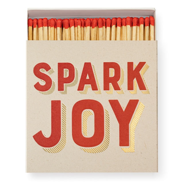 Quadratische Matchbox „Spark Joy“: roter Typo mit Goldfolien-Schatten; 125 lange Streichhölzer, natur mit roten Köpfen.