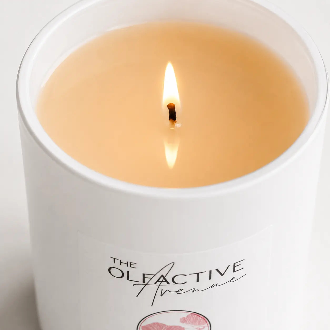 Duftkerze Peach & Rose von The Olfactive Avenue — Nahaufnahme der Flamme im weißen Glas