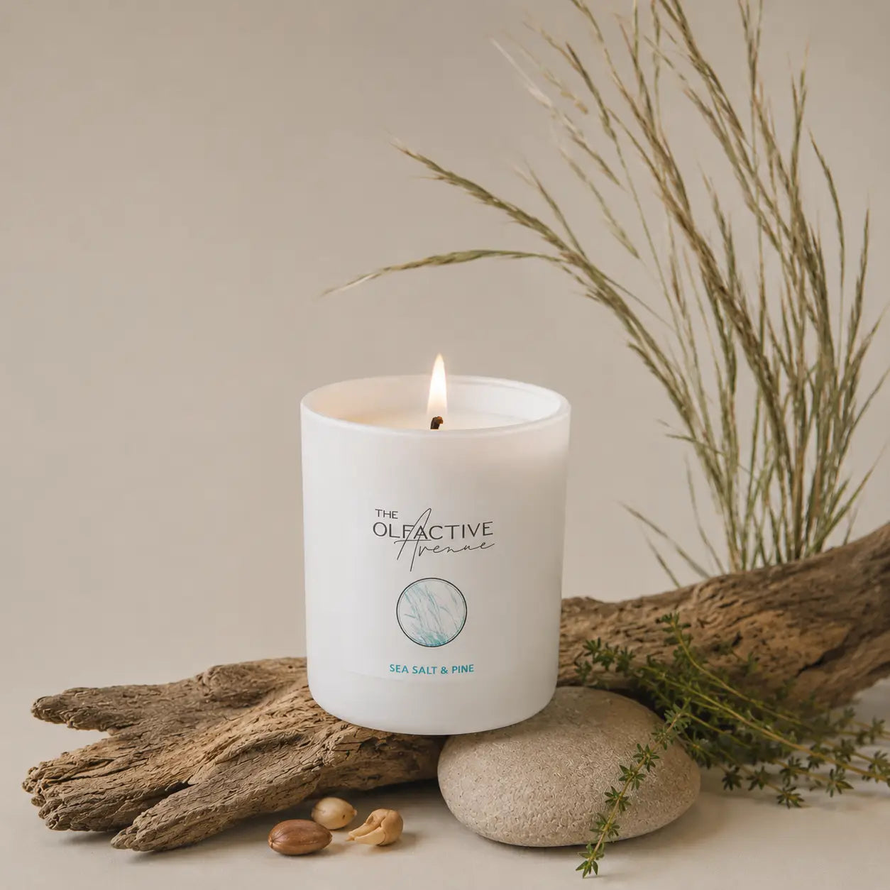 Duftkerze Sea Salt & Pine von The Olfactive Avenue — brennend mit Holz, Stein und Küstenakzenten
