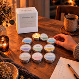 Discovery Set von The Olfactive Avenue: 9 Mini-Duftkerzen in Aluminiumdosen vor der Produktbox, eine brennt [KI]