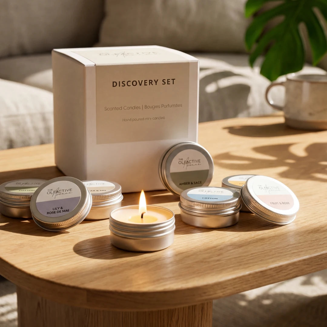 Discovery Set von The Olfactive Avenue – 9 Mini-Candles auf Eichentisch, eine brennend, mit Duftkerzen in Cedar & Moss, Cotton, Peach & Rose und weiteren Duftsorten