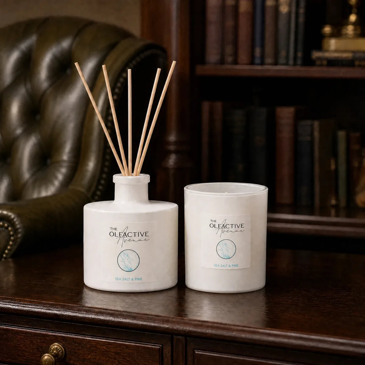 Geschenkset Deluxe von The Olfactive Avenue mit Raumduft-Diffuser und Duftkerze Sea Salt & Pine auf dunklem Holzschreibtisch in stilvoller Bibliotheksatmosphäre [KI]